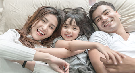 An Asian couple with their daughter on a bed